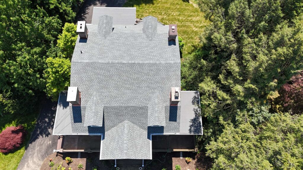 View of a tranquil multi-faceted roof with chimneys, surrounded by greenery—Strath Haven historic restoration focus.