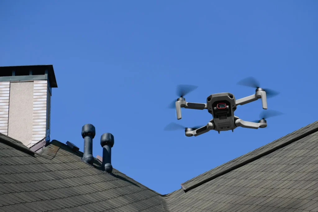 A drone hovers above a house featuring a prominent chimney, capturing aerial views of the property.